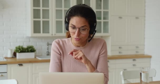 Hermosa mujer joven en gafas y auriculares celebración de videollamada. — Vídeos de Stock