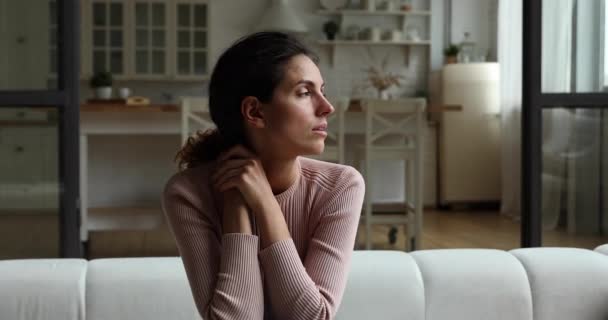 Pensive young woman sitting on sofa at home. — Stock Video