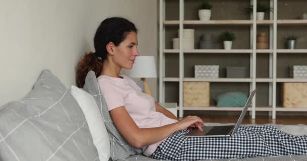 Boldog nyugodt csinos nő számítógéppel, pihentető az ágyban. — Stock videók