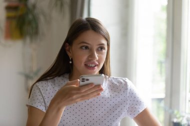 Elinde modern cep telefonu olan gülümseyen genç bayan sesli mesaj kaydediyor.