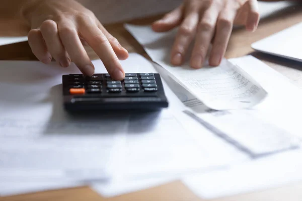 Jonge vrouw met ontvangstbewijs met behulp van rekenmachine om de betaling bedrag te controleren — Stockfoto