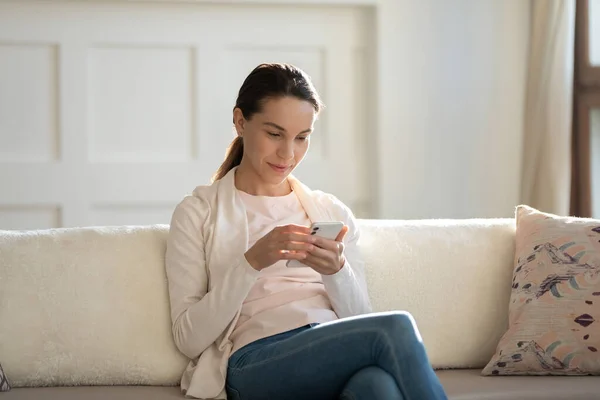 Cerca de mujer joven atractiva usando el teléfono, sentado en el sofá — Foto de Stock