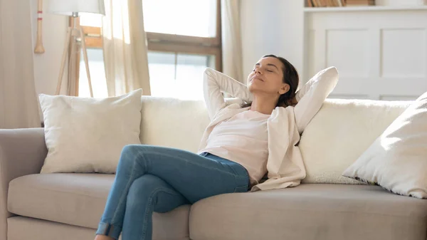 Mujer atractiva pacífica inclinada hacia atrás, descansando en un sofá acogedor — Foto de Stock