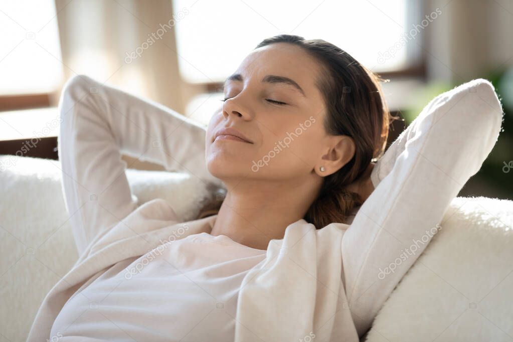 Close up calm woman with closed eyes relaxing on couch