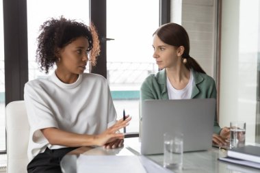 Kendine güvenen Afrikalı Amerikalı iş kadını yeni çalışanı eğitiyor, dizüstü bilgisayar kullanıyor.