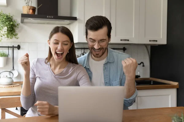 Οικογενειακό ζευγάρι ουρλιάζοντας από χαρά από την οθόνη του φορητού υπολογιστή στην κουζίνα — Φωτογραφία Αρχείου