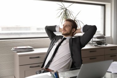 İş bittikten sonra ofis sandalyesinde uzanan memnun iş adamı.