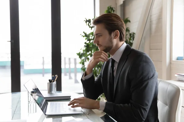 Vue de côté homme d'affaires réfléchi regardant l'écran d'ordinateur portable, réfléchir tâche — Photo