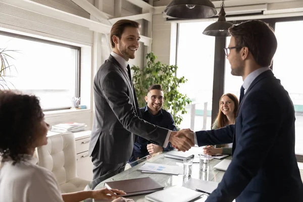 Socios de negocios felices estrechando la mano en la reunión, de pie en la sala de juntas — Foto de Stock