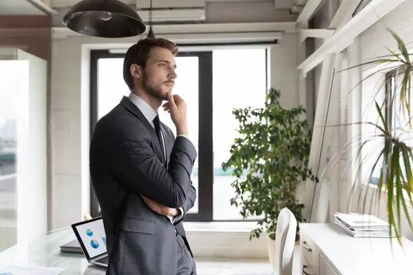 Thoughtful businessman wearing suit touching chin, looking to aside — Stock Photo, Image