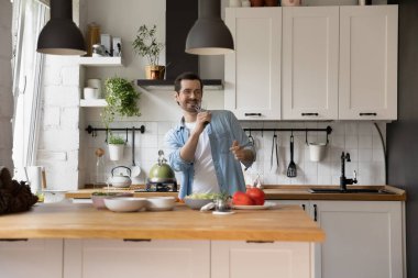 Mutlu genç adam hayali mikrofonda romantik bir akşam yemeği pişiriyor.