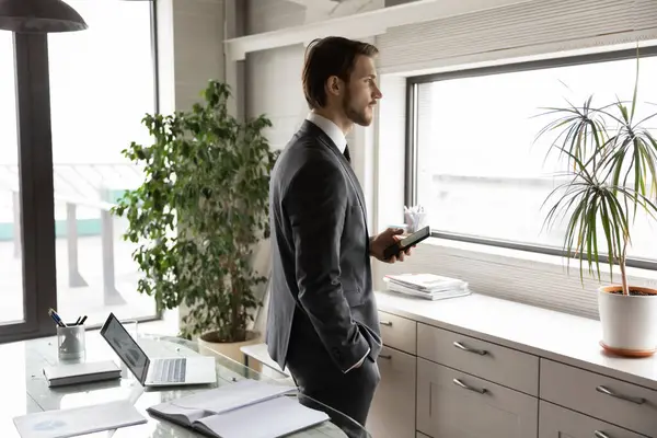 Verträumter Geschäftsmann mit Telefon, Blick in die Ferne, träumt im Büro — Stockfoto