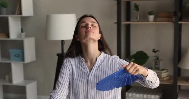 Нещаслива молода бізнес-леді дме прохолодне повітря з паперовим вентилятором . — стокове відео