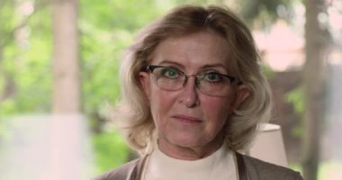 Gözlüklü yaşlı, mutlu yaşlı kadın kameraya bakıyor..