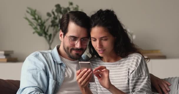 Ζευγάρι κάθονται στον καναπέ κρατώντας smartphone γιορτάζουν online νίκη στοιχημάτων — Αρχείο Βίντεο