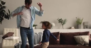 Küçük çocuk evde babasıyla dans ediyor.