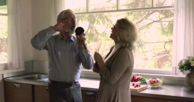 Mutfakta şarkı söyleyen enerjik orta yaşlı çift.