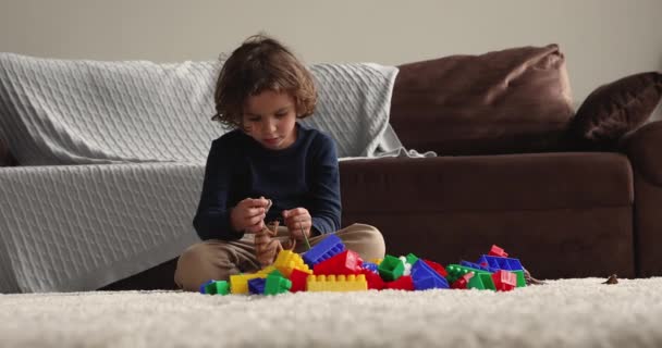 Kleine jongen zit alleen in de woonkamer spelen dinosaurus speelgoed — Stockvideo