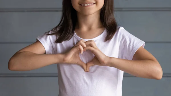 Close up smiling adorable little girl showing heart gesture — Stock Photo, Image