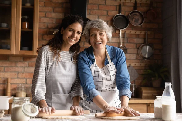 Head shot portrait smiling mature woman with daughter cooking pastry