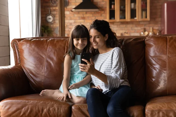 Mãe sorridente com filhinha usando smartphone, posando para selfie — Fotografia de Stock