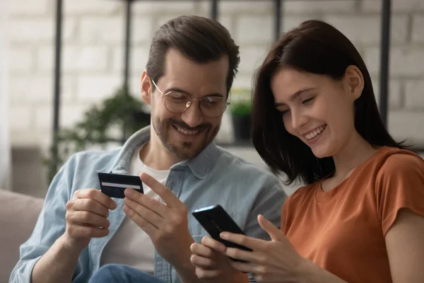 Primer plano feliz pareja joven que paga en línea, utilizando el teléfono inteligente — Foto de Stock