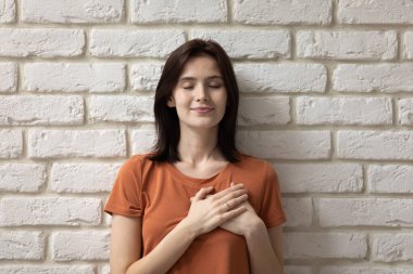 Minnettar bir portre. Dilek dolu genç bir kadın göğsünde el ele tutuşuyor.