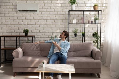 Klimalı uzaktan kumanda kullanan gözlüklü bir adam.