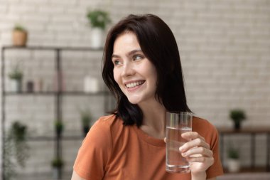 Kafasından vurulmuş, gülümseyen kadın elinde bir bardak saf maden suyu tutuyor.