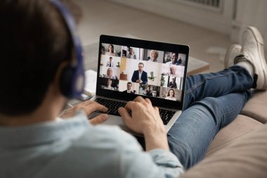 Arkadaki adam video konferansında, dizüstü bilgisayar kullanıyor.