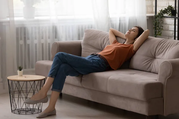 Jeune femme paisible se détendre sur un canapé confortable à la maison — Photo