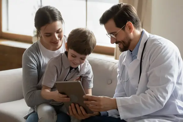 El médico varón que cuida utiliza el comprimido en consulta con el paciente pequeño —  Fotos de Stock