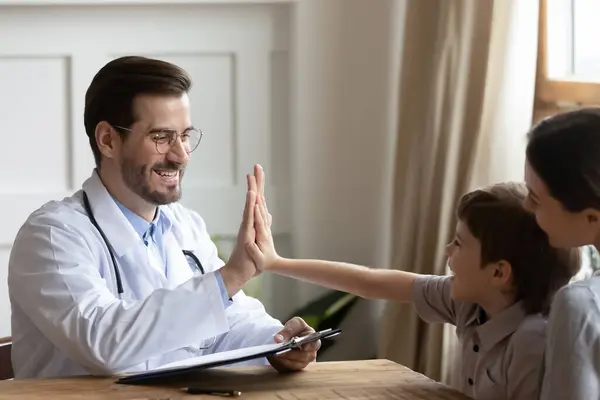 Feliz médico masculino animar niño pequeño en la consulta —  Fotos de Stock