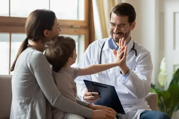 Feliz doctor tener divertido saludo con niño pequeño paciente —  Fotos de Stock