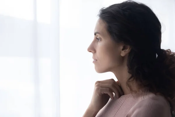 Thoughtful young caucasian woman standing near window. — Stock Photo, Image