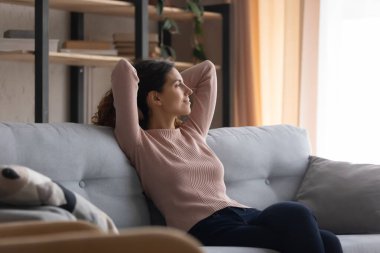 Rahat, genç, gülümseyen kadın rahat koltukta oturuyor..