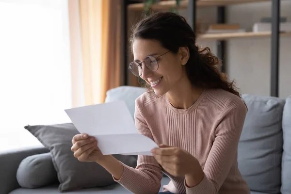 Glad ung kvinna i glasögon läser papper brev. — Stockfoto