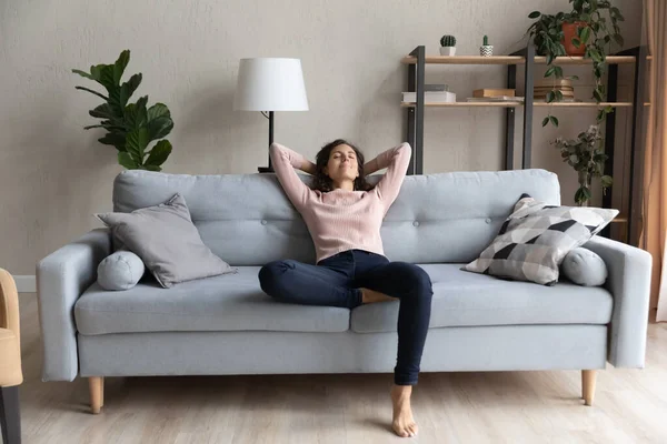 Vreedzame gelukkige jonge vrouw ontspannen op comfortabele bank. — Stockfoto