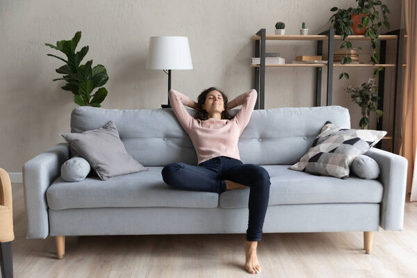 Peaceful happy young woman relaxing on comfortable sofa.
