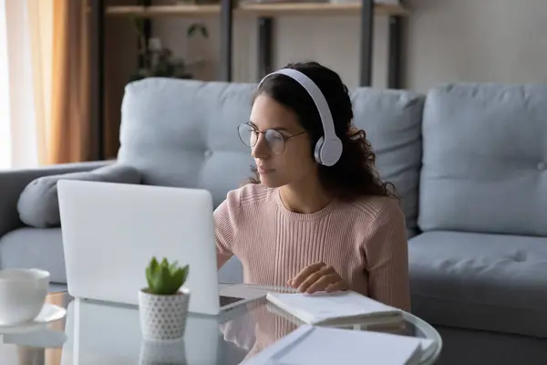 Концентрированная молодая женщина слушает онлайн лекцию дома. — стоковое фото