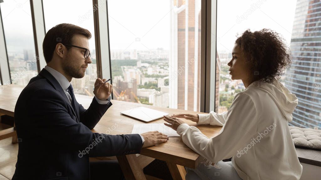 Confident man consultant talking with african female customer in office