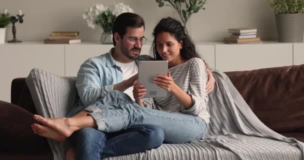 Małżeństwo relaksujące się na kanapie za pomocą tabletu — Wideo stockowe