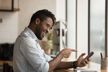 Gülen Afrikalı adam telefon ekranını işaret ederek arkadaşıyla sohbet ediyor.