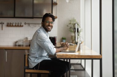 Gülümseyen siyah milenyum adamı bilgisayardan dikkati dağılmış kameraya bakıyor.