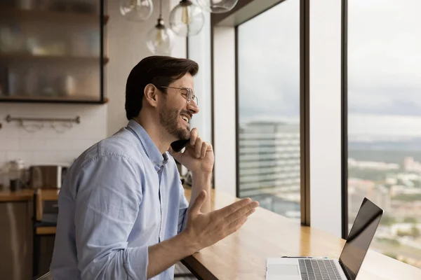 Happy male programmer distracted from pc to answer phone call — Stock Photo, Image