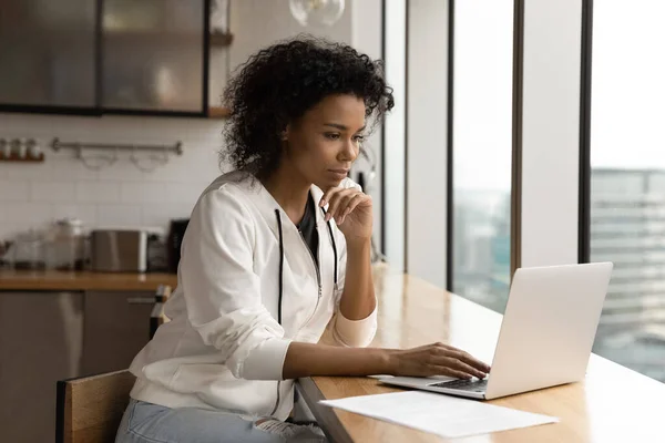 Jeune africaine travail féminin en ligne à l'aide d'un ordinateur portable à l'appartement moderne — Photo