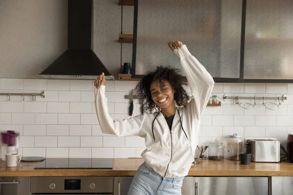 Positieve jonge Afrikaanse vrouw dansen in de keuken in goed humeur — Stockfoto