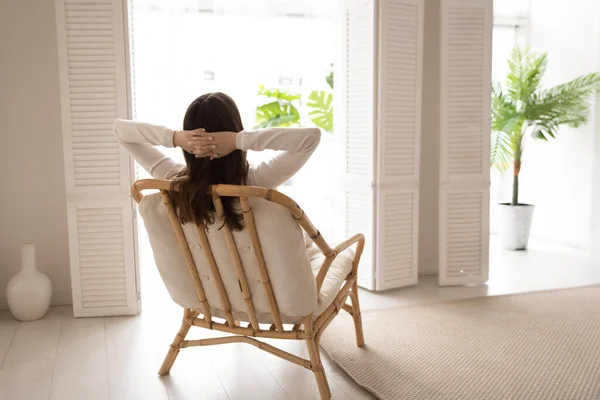 Вид ззаду жінка відпочиває в затишному кріслі вдома — стокове фото