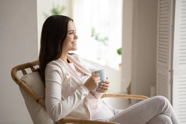 Happy young woman relax in chair drinking tea — Stock Photo, Image