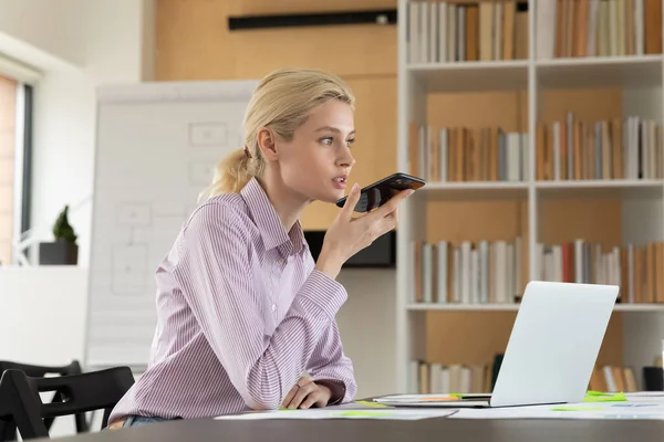 Female millennial employee recording audio message on smartphone — Stock Photo, Image